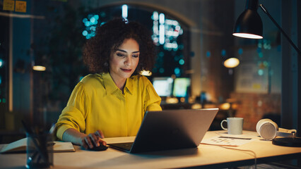 Wall Mural - Successful Arab Female Sitting in Creative Agency Alone in the Evening, Manager Working on Implementing Business Strategy for Client. Excited Specialist Writing Corporate Project Plans on Computer.