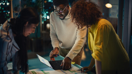 Poster - Group of Young Successful Businesspeople Making a Team Meeting in Conference Room in Creative Agency. Excited Diverse Team Using Laptop Computer, Discussing a New Corporate Strategy. Evening at Work.