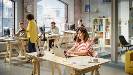 Wall Mural - Portrait of Young Female Executive Assistant Working on Scheduling Meetings. Statistics and Charts are on Display on Papers.