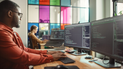 Poster - African American Man Writing Code on Desktop Computer With Multiple Monitors Set Up and a Laptop in Creative Office. Professional Data Scientist Using Software to Analyze Information From Internet.