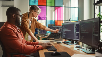 Wall Mural - African American Software Engineer Shows Code on Desktop Computer to Female Project Manager in Stylish Office. Black Man And Caucasian Woman Discussing Progress of AI Application Development.