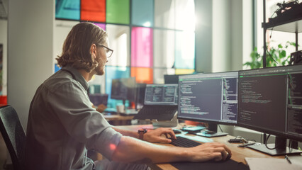 Wall Mural - Professional Male Programmer Writing Code on Desktop Computer With Multiple Displays in Stylish Office. Caucasian Man Does Data Scraping For Artificial Intelligence Innovative Start-Up.