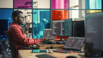 Poster - African American Man Writing Lines Of Code On Desktop Computer With Multiple Monitors and Laptop in Creative Office. Male Data Scientist Working on Innovative Online Service For Start-up Company.