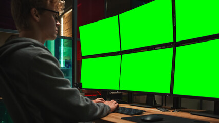 Wall Mural - Young Caucasian Man Writing Code on Professional Six Monitors Setup With Green Screen Chromakey. Male Cyber Security Expert Controlling Data Protection System in International Intelligence Agency.