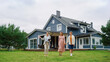 © Gorodenkoff - Real Estate Agent Showing a Beautiful House to a Young Happy Couple. People Walking Outside on a Lawn, Talking with Businesswoman, Discussing Buying a New Home.
