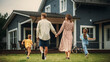 © Gorodenkoff - Young Beautiful Couple Walking Outdoors Towards the Country House, Holding Hands. Their Little Son and Daughter Running Together with Them. Young Modern Family at Home, Footage from The Back.
