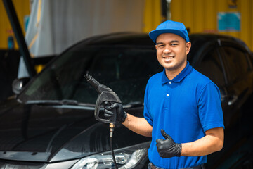 Wall Mural - Man worker washing car service. Car wash cleaning station high pressure water. Employees clean a vehicle professionally.