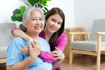 Wall Mural - Portrait of a daughter with an elderly Asian mother smiling happily. Sit and cuddle in the living room of the house. Family concept. Health care.