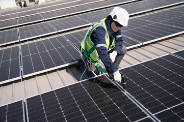 Caucasian engineer man use electric screwdriver working with solar panel on roof factory