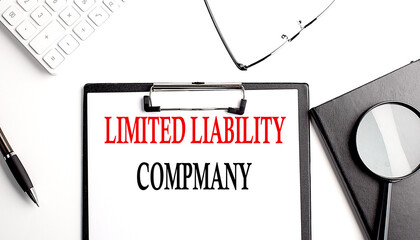Poster - LIMITED LIABILITY COMPANY text written on paper clipboard with office tools