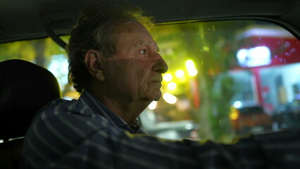 Older man driving at night in city. Profile closeup face of mature senior male driver person drives in evening