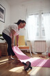 © astrosystem - Woman training inside the living room, exercising at home.