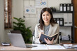 © amnaj - Asian businesswoman secretary sitting happily working on laptop Take notes attentively and smile happily doing the assignments.