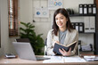 © amnaj - Asian businesswoman secretary sitting happily working on laptop Take notes attentively and smile happily doing the assignments.
