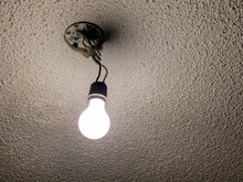 Glowing Bare Light Bulb Hanging From A Ceiling Fixture