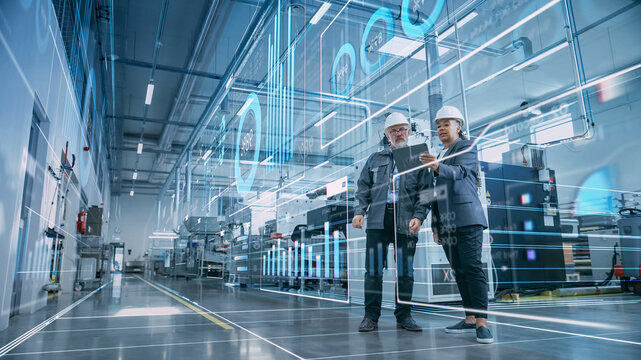 Fototapete - Factory Digitalization: Two Industrial Engineers Use Tablet Computer, Visualize the Wall of Big Data Statistics, Optimization of High-Tech Electronics Facility. Industry 4.0 Machinery Production