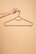 © vladimirfloyd - Woman finger holding empty hanger on a beige studio background