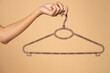 © vladimirfloyd - Woman finger holding empty hanger on a beige studio background