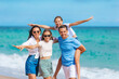 © travnikovstudio - Family of four have fun together on beach vacation in Florida