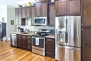 Wall Mural - A new kitchen with dark wood cabinets, hardwood floors and stainless steel appliances