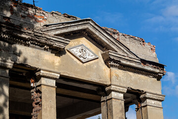 Stalinist architecture style entrance facade of shabby old Soviet building on a sunny day with blue sky