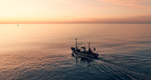 Fishing Boat Catching Fish At Sunset Aerial View From Drone. Small Fishing Trawler Ship On Sea Surface.