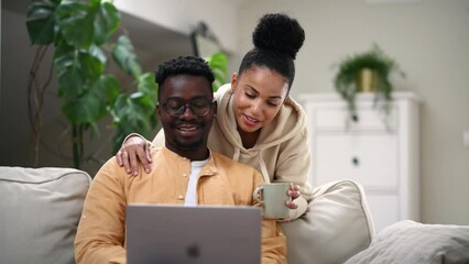 Diverse couple using laptop together at home
