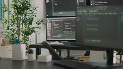 empty desk with multiple monitors displaying server code and programming language, compiling in soft