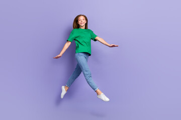 Poster - Full length photo of shiny adorable small lady wear green t-shirt jumping high walking isolated violet color background