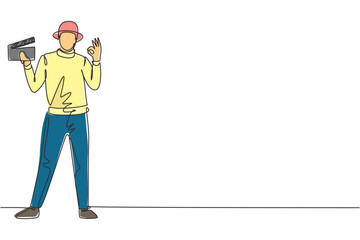 Fototapete - Continuous one line drawing film director stands with gesture okay holding clapperboard and prepare camera crew for shooting at television studio. Single line draw design vector graphic illustration