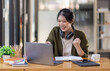 © David - Young adult happy smiling Hispanic Asian girl student wearing headphones talking on online chat meeting using laptop in university campus or at virtual office. College female student learning remotely