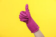 © splitov27 - Hand in purple rubber cleaning glove shows thumbs up on a yellow background. House cleaning and housekeeping concept