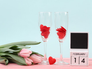 Wall Mural - Two glasses with hearts, tulips and a calendar with the date February 14 on a pastel background. Valentine's day