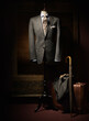 © Designpics - Suit jacket, shirt and tie displayed on dress form with suitcase, coat, gloves and an umbrella beside on floor, studio shot