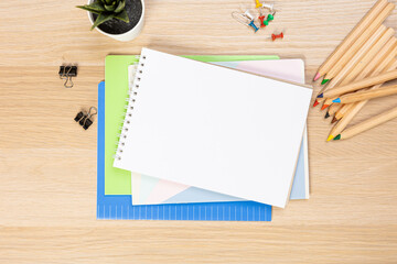 Wall Mural - Notebook mockup with school stationery on a wooden table. back to school concept. Blank notepad with copy space. list of goals and plans for new year 2023