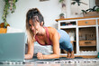 © simona - Healthy sport fitness lifestyle at home using laptop to watch and follow online lessons. Cheerful woman on the floor doing push ups plank exercise to build a perfect healthy body alone. Workout people