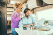 © simona - Happy couple man and woman working and using together a laptop computer inside a camper van planning holiday vacation destination and living vanlife lifestyle in freedom. People travel and tourism
