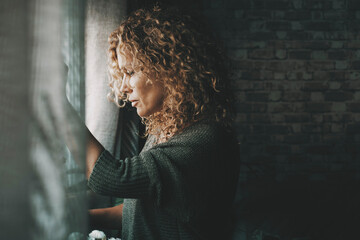 Sadness worried woman inside home near the window. Bad unhappy day. Side view of female people sad with depression. Problems and home domestic loneliness. House couple violence. Wife alone in trouble