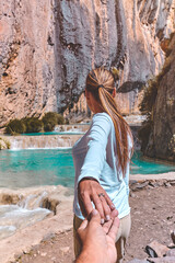 Closeup Young woman holding man hand while leading him on nature outdoor. Concept about travel love