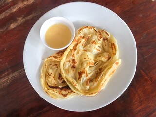 Abstract process photo of Roti canai with a cup of condensed milk as a sweet recipe in Thailand. That also calls roti prata which is an Indian flatbread dish can be cooked sweet or savoury variations