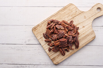 Poster - Tasty pecan-nut on a wooden board on white color table 