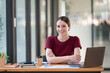 © Songsak C - An attractive businesswoman sitting at her desk, arms crossed, smiling and looking at the camera.