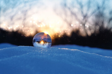 magic clear quartz ball on snow, winter natural blurred evening background. christmas, new year wond