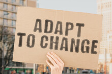 The Phrase " Adapt To Change " Is On A Banner In Men's Hands With Blurred Background. Preparation. Work. Planning. Successful. Self. Risk. Bet. Hazard. Investment. Gamble. Crisis. Chance. Way