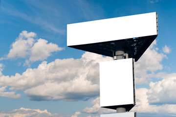 Mock up - two blank white billboards or large advertising displays against blue sky with white clouds. Consumerism, white screen, template, mock up and copy space concept