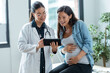 © nenetus - Female gynecologist doctor showing to pregnant woman ultrasound scan baby with digital tablet in medical consultation.