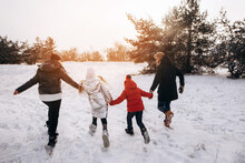 Father, Mother And Two Children Daughters Are Having Fun And Playing On Snowy Winter Walk In Nature. Happy Family At Sunset. Frost Winter Season.