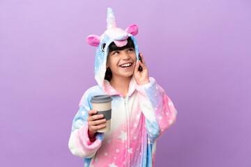 Sticker - Little kid wearing a unicorn pajama isolated on purple background holding coffee to take away and a mobile