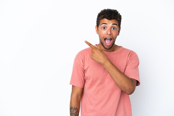 Young handsome Brazilian man isolated on white background surprised and pointing side