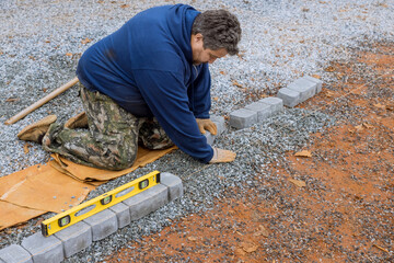 Canvas Print - An employee of construction company installing precast concrete pavers stone for road sidewalk on construction site